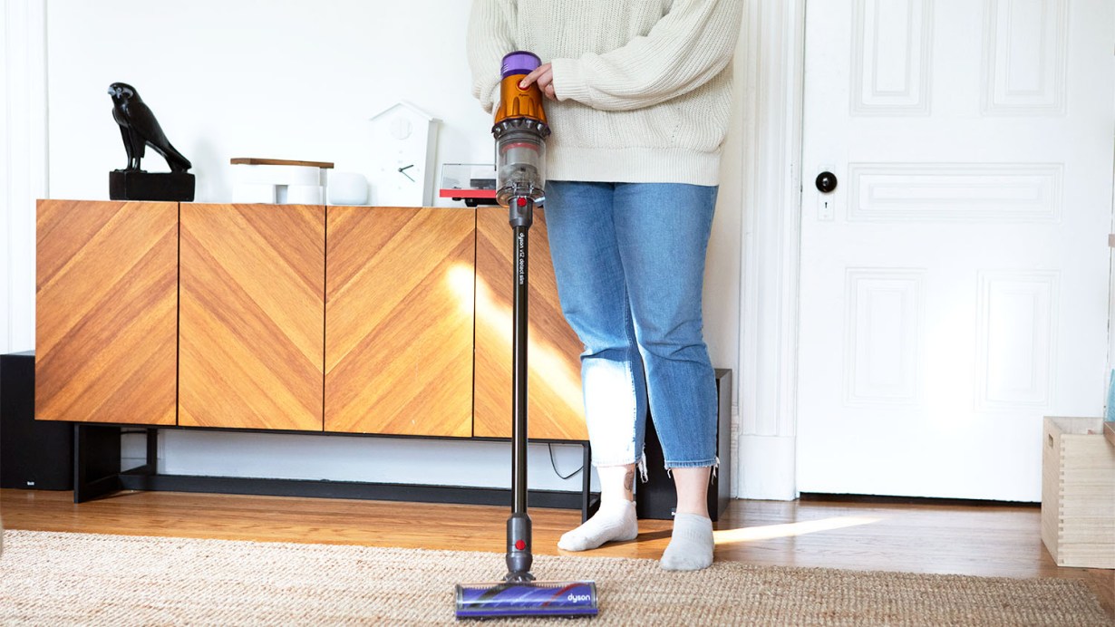 Person using stick vacuum on carpet