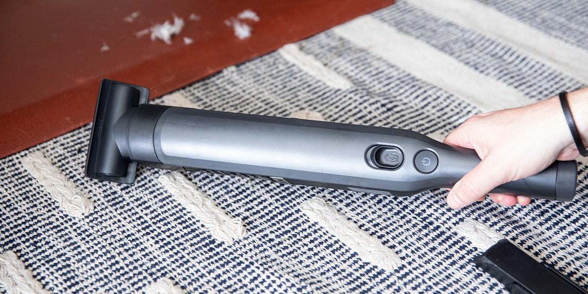 Person using handheld vacuum on area rug