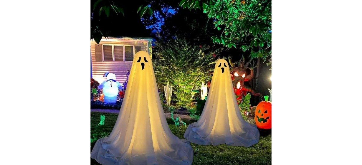 Two spooky Halloween ghosts in front yard at night Two spooky Halloween ghosts in front yard at night